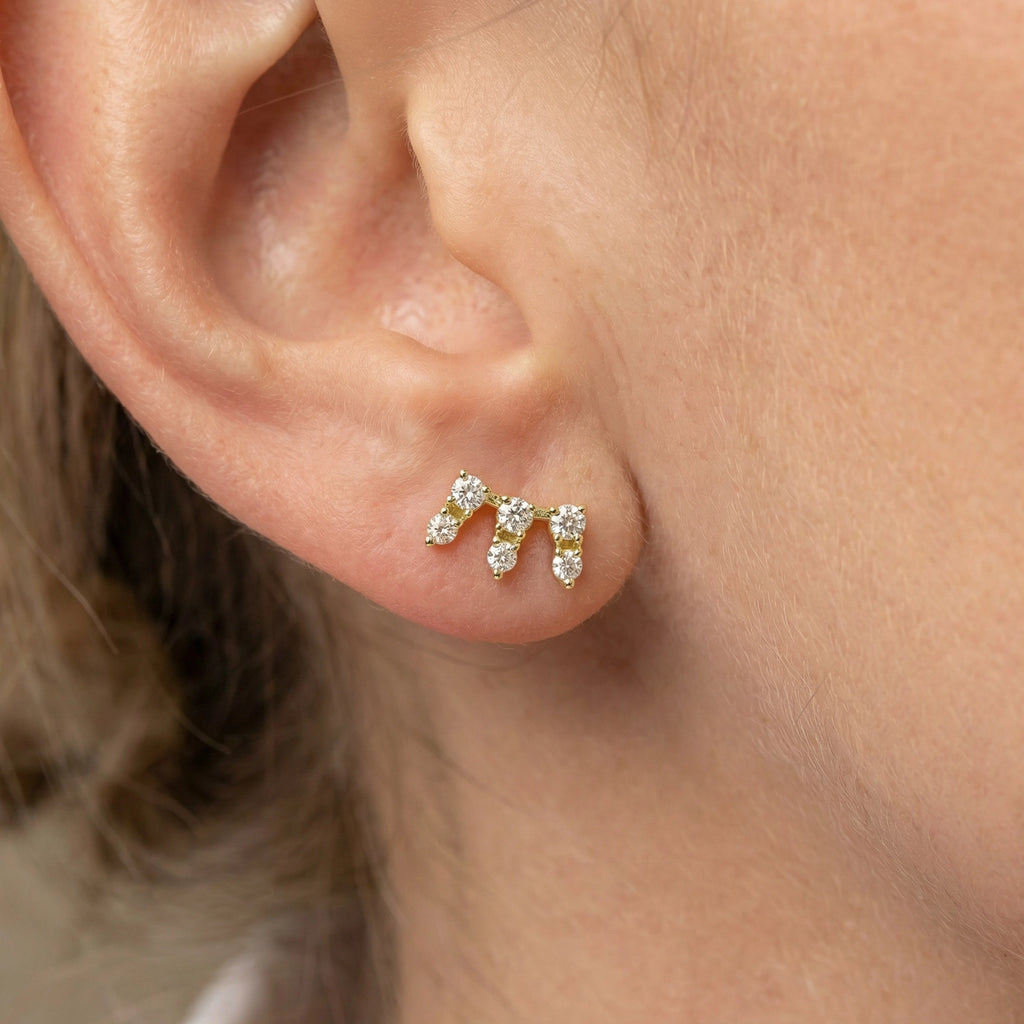 A sleek pair of 14K Yellow Gold Seven-Stone Diamond Climber Earrings on ear.