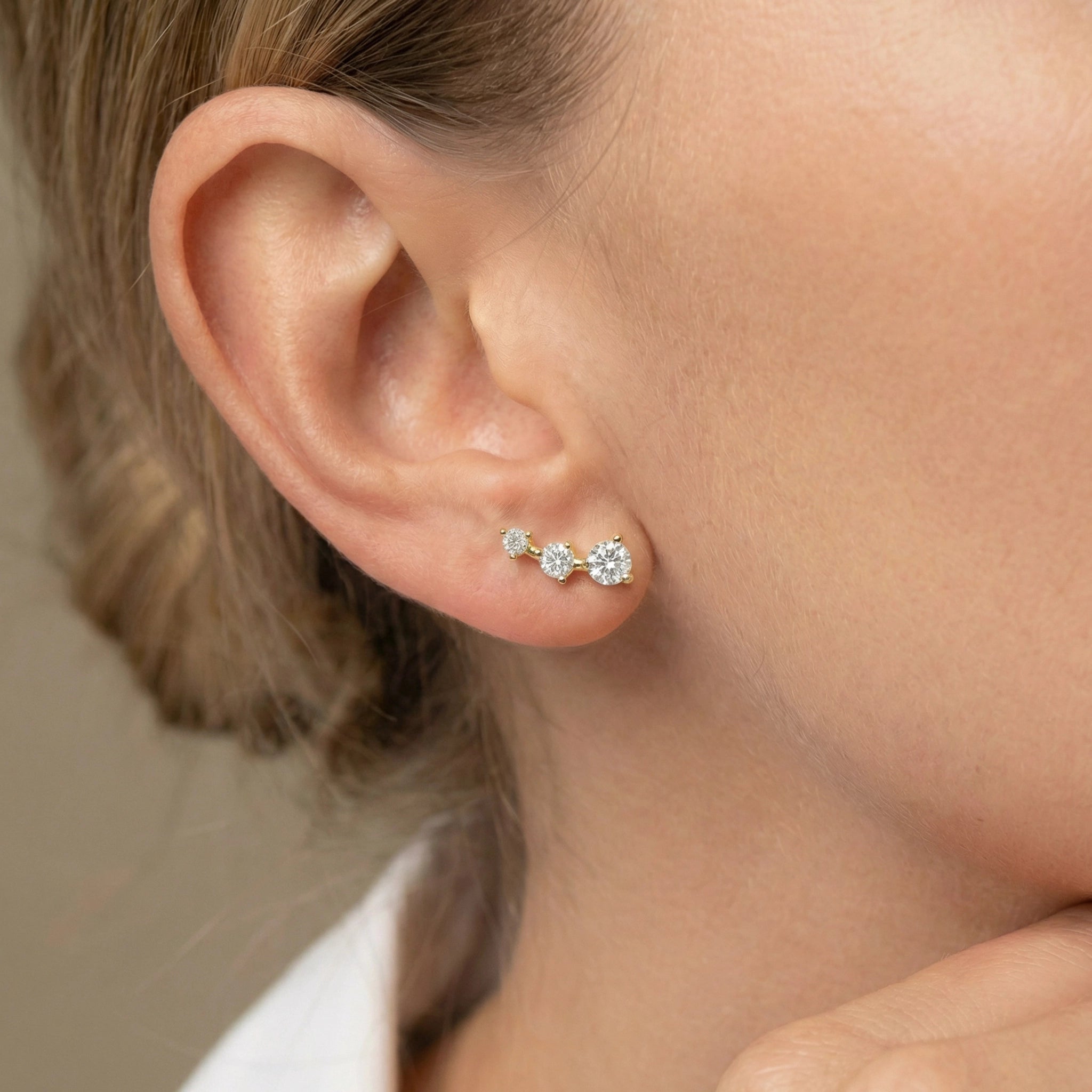 A sleek 14K yellow gold ear crawler earring on ear.