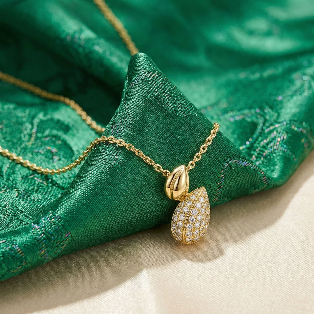 Gold necklace with a teardrop pendant on green fabric