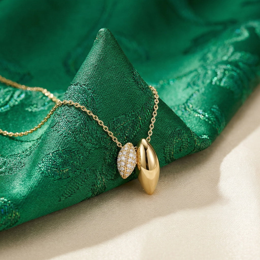 Gold necklace with leaf-shaped pendant on green fabric