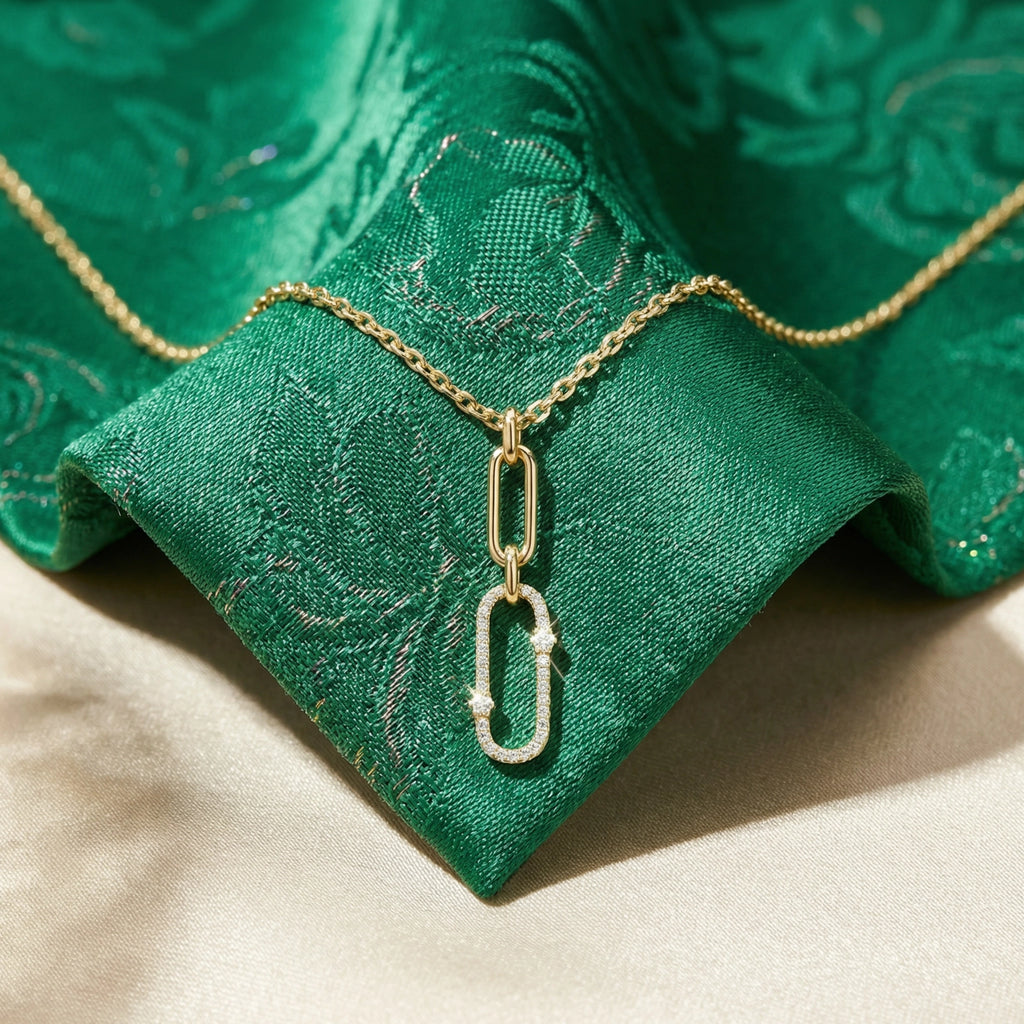 Gold necklace with a chain pendant on a green fabric background