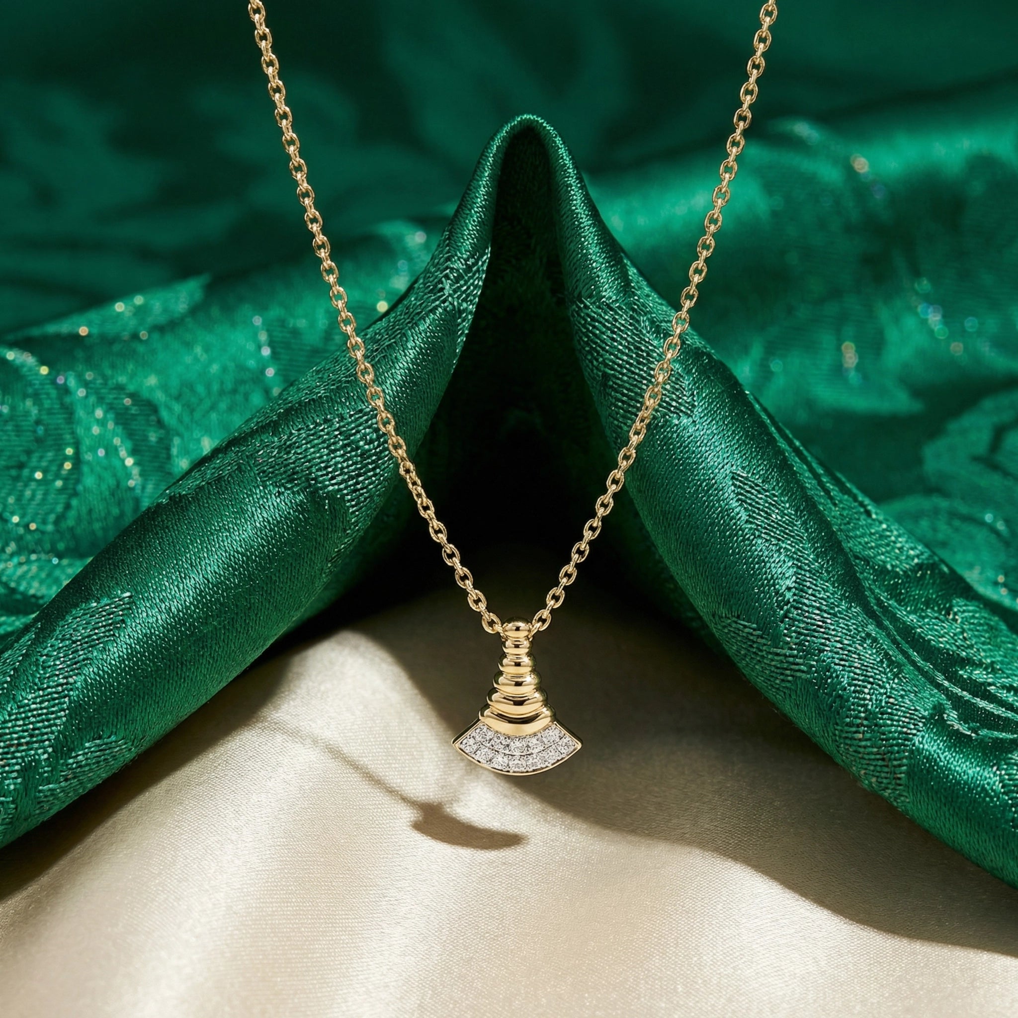 Gold necklace with a diamond pendant on a green fabric background