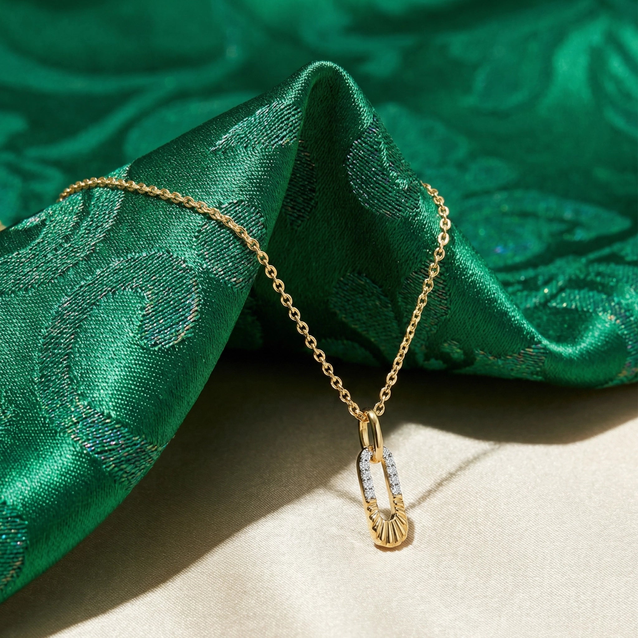 Gold necklace with a pendant on green fabric