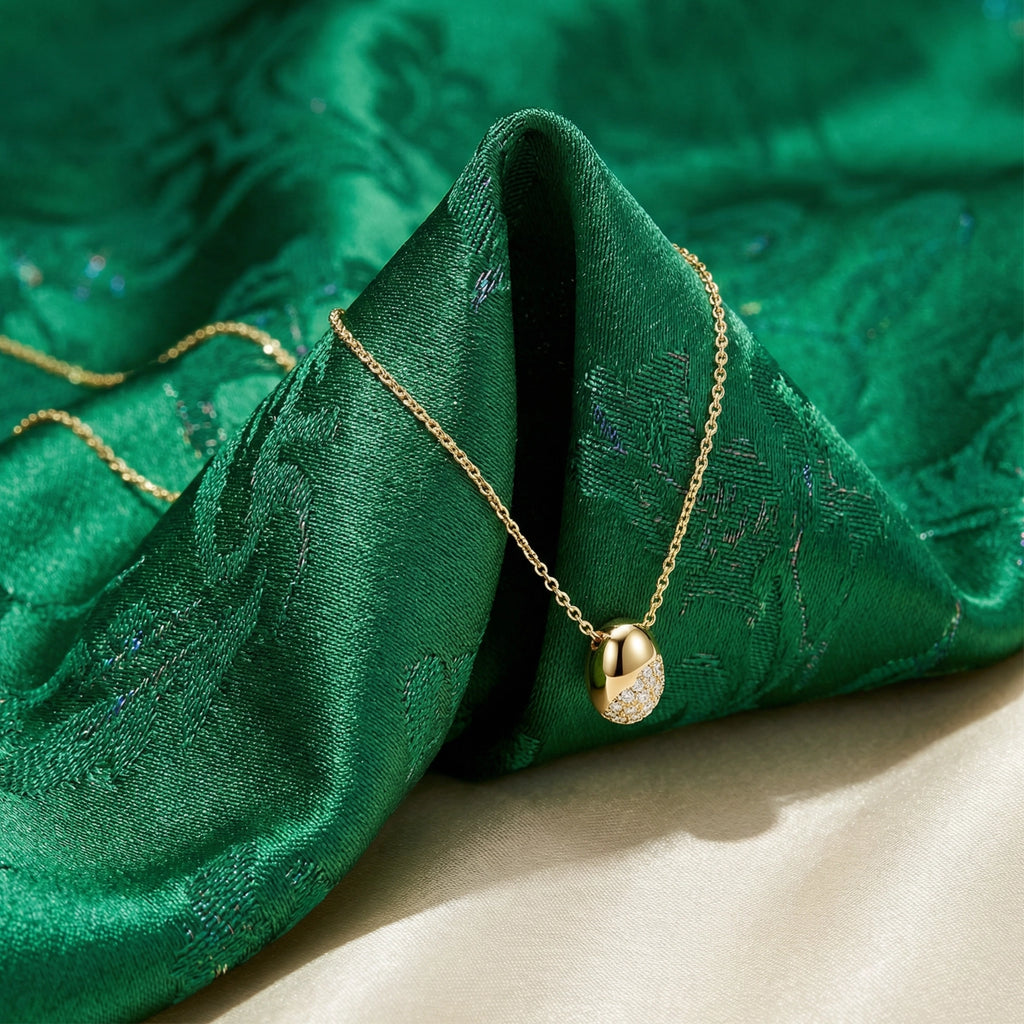 Gold necklace with a round pendant on green fabric