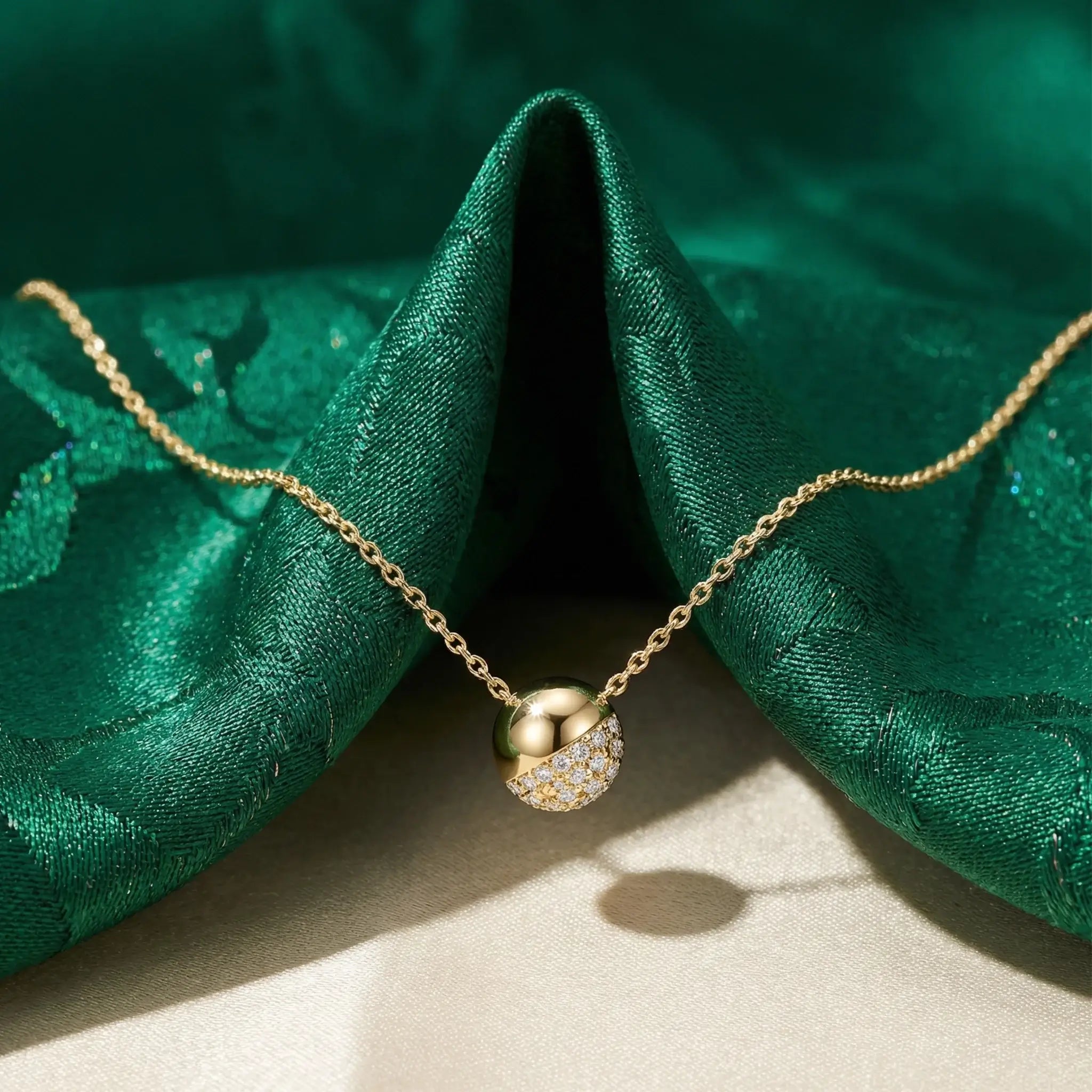 Gold necklace with a pendant on green fabric