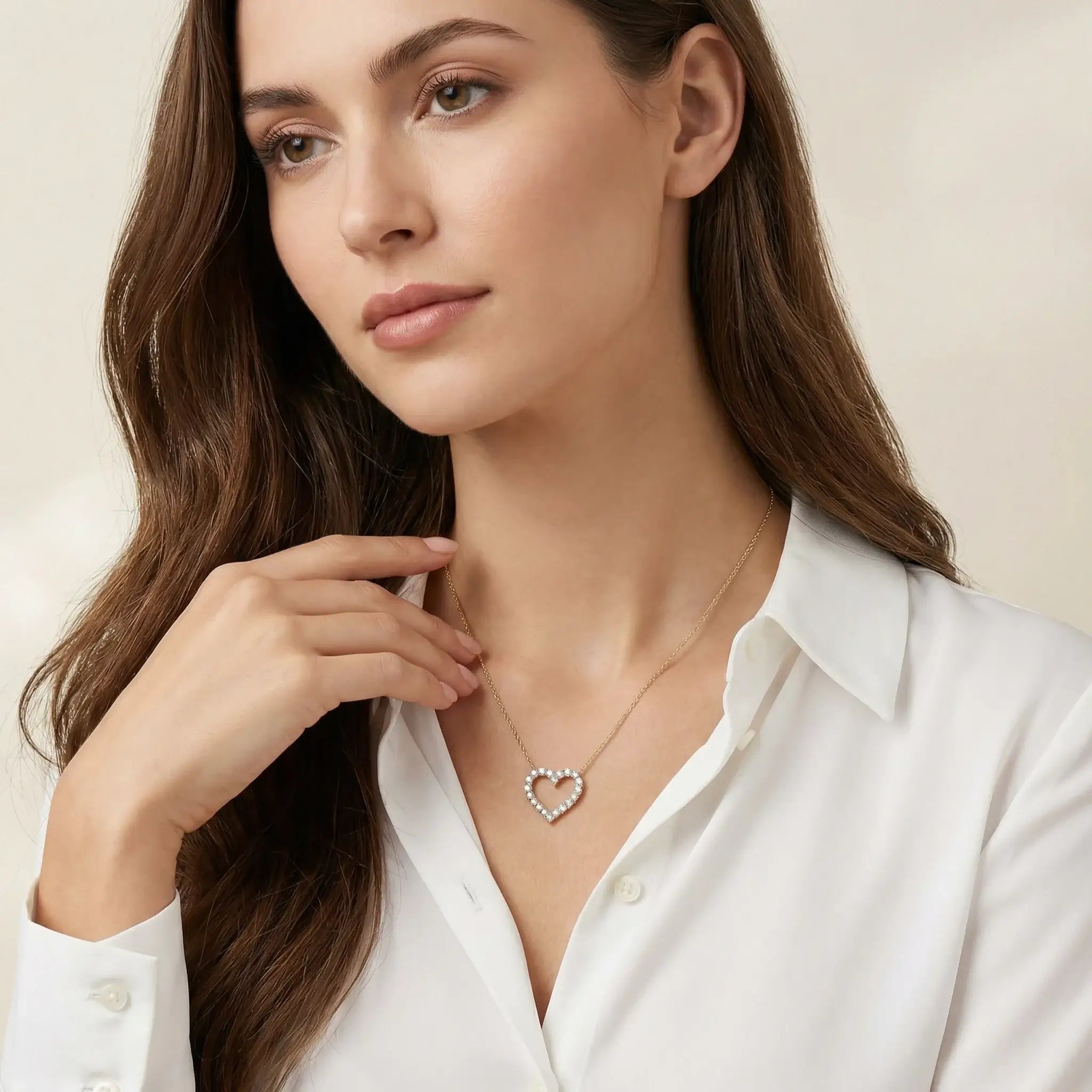 Woman wearing a diamond heart pendant necklace against a neutral background