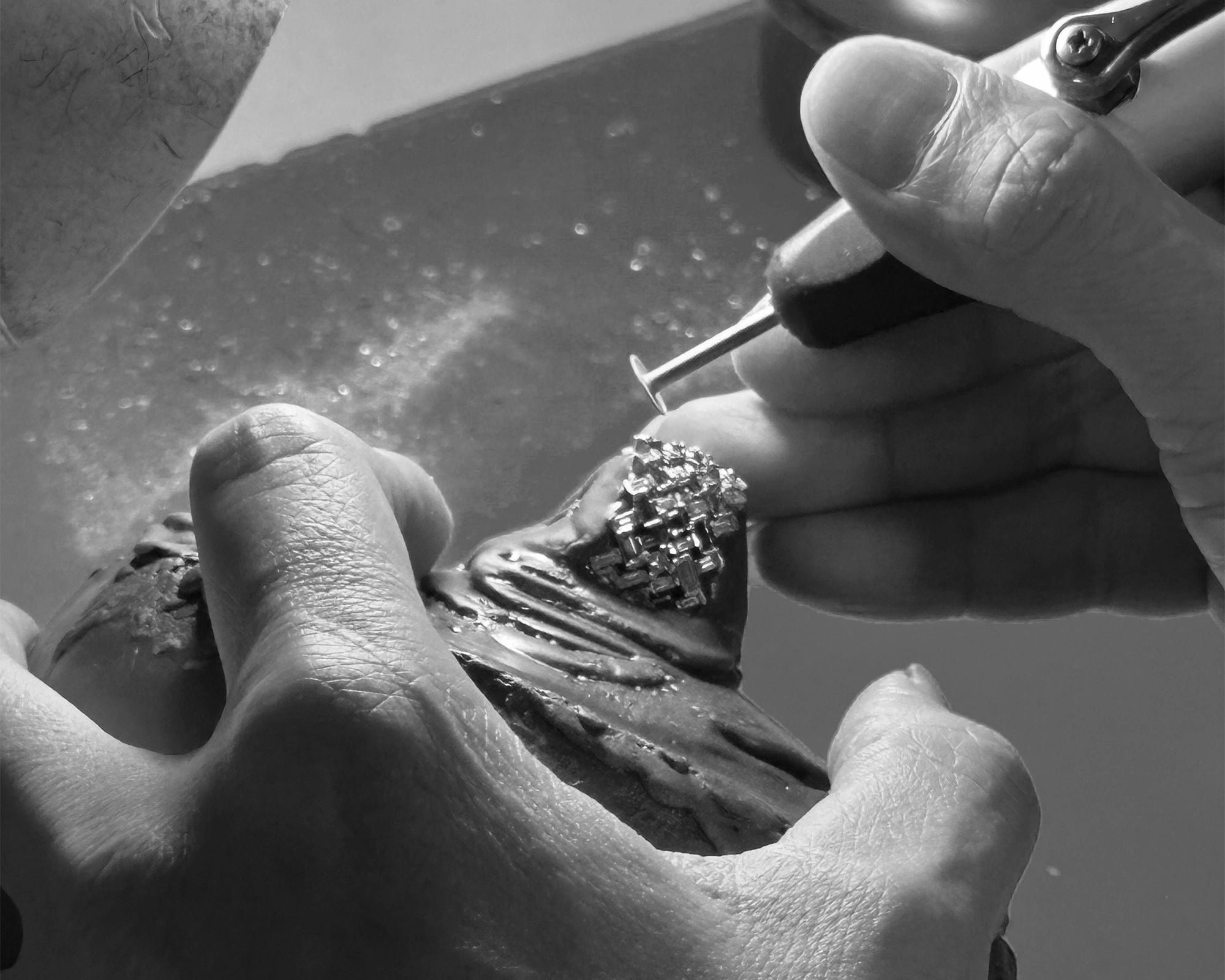 Close-up of hands working on a diamond ring with tools