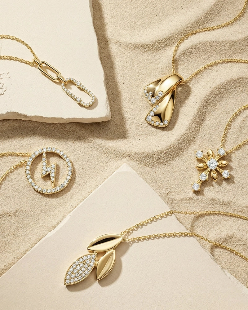A curated flat lay of BeBling pendant necklaces showcasing a variety of styles: a solitaire diamond, a geometric bar, and an initial pendant in different chain lengths.