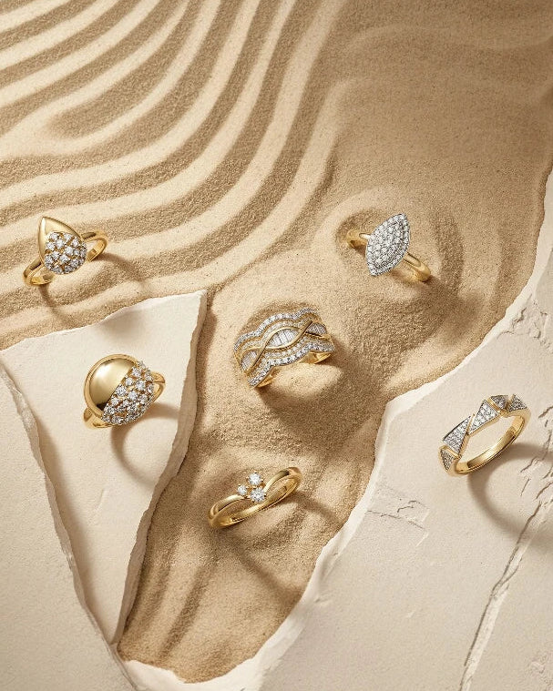 Gold rings with diamonds on a textured beige surface
